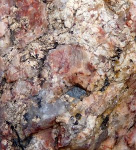 Close-up of rock surface with reddish and white crystalline segments