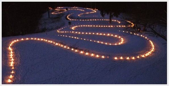 Nighttime photo of candles outlining a snow-crusted Serpent Mound