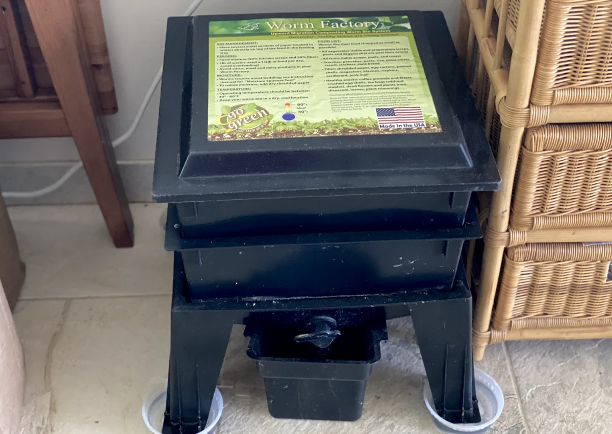 Low square black worm bin stacked with two trays to hold worms, covered by a lid that says Worm Factory