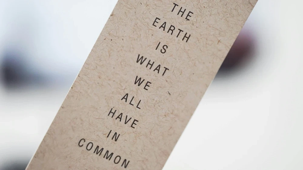 Close-up of a bookmark, on the front of which is written: THE EARTH IS WHAT WE ALL HAVE IN COMMON.