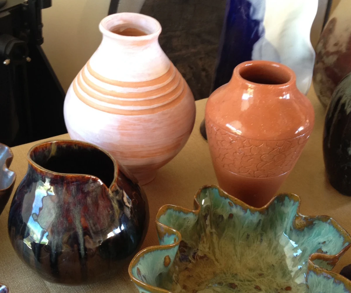 Tall terra-cotta vases, a round brown-black shiny pot, a green-glazed bowl with scalloped edges