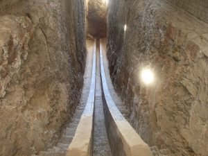 An ancient passageway sloping downward between tall rough rock walls