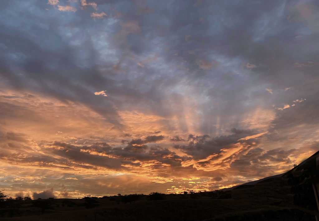 Sunrise breaks in orange across a dark sky.