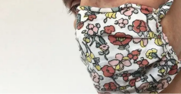 Extreme close-up of a face in profile wearing a flower-printed cloth face mask